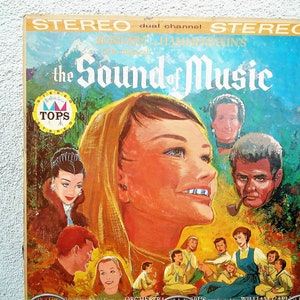 May include: Vintage vinyl record album cover for "The Sound of Music." The cover features a colorful illustration of a woman with a headscarf, surrounded by other characters and the title in large, stylized lettering. The album is labeled "Stereo."