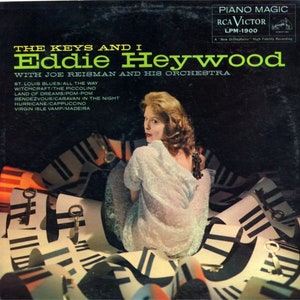 May include: Vintage album cover for "The Keys and I" by Eddie Heywood. The cover features a woman in a light-colored dress, surrounded by piano keys and keys. The album title and artist's name are in bold text, with the RCA Victor logo in the upper right corner.