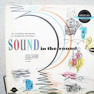 May include: Vintage vinyl record album cover titled "SOUND in the round." The cover features colorful illustrations of a train, a marching band figure, and other graphics. Text includes "An astounding introduction to stereophonic recording..." and "CONCERT-DISC STEREO."