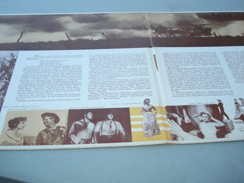 May include: A vintage record album cover featuring a black and white photo of a horse-drawn carriage. The album cover also includes text about the musical "Oklahoma!" and features photos of the cast members. The album cover is in good condition with some wear and tear.
