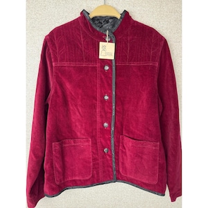 May include: A deep red velvet jacket featuring a mandarin collar, long sleeves, and a front button closure. The jacket includes two large patch pockets on the front, black trim along the edges, and a tag with the text "TIBETAN TRADER" attached.