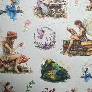 May include: A collection of fairy-themed stickers featuring various illustrations of fairies in different settings. The stickers showcase fairies with wings, dressed in flowing gowns, engaged in activities like reading, crafting, and resting amidst nature. The color palette includes soft blues, purples, and greens.