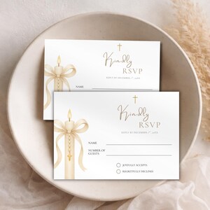 Op de afbeelding: Twee RSVP-kaarten met een kaarsontwerp. De kaarten bevatten de tekst "Kindly RSVP" en bevatten ruimte voor de naam en het aantal gasten. Het ontwerp bevat een kruis en een strik, met een zacht, neutraal kleurenpalet.