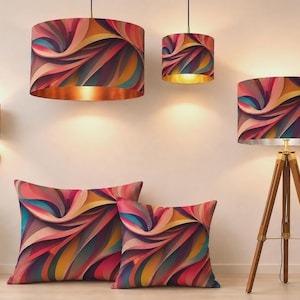 Op de afbeelding: Een collectie woonaccessoires met een wervelend abstract patroon in roze, oranje, gele en blauwgroene tinten. De set bevat twee cilindervormige hanglampen, een wandlamp, een statiefvloerlamp en twee vierkante sierkussens.