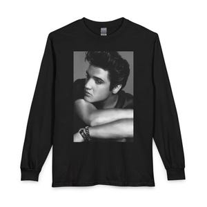 May include: Black long-sleeve shirt featuring a black and white portrait of Elvis Presley. The portrait shows Elvis with his arms crossed and a bracelet on his wrist. The shirt has a crew neck and long sleeves.