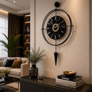 Könnte beinhalten: Eine schwarze Wanduhr mit einem kreisförmigen Rahmen, einem schwarzen Zifferblatt, goldenen Ziffern und dünnen weißen Zeigern. Die Uhr verfügt über eine vertikale Stützstruktur und ein nach unten gerichtetes, schwarzes, konisches Pendelgewicht.