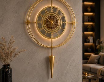 May include: A gold-toned wall clock featuring a circular frame with an integrated light ring. The clock face displays Roman numerals and a central geometric pattern. A vertical rod extends downward, ending in a pointed, cone-shaped pendulum weight.