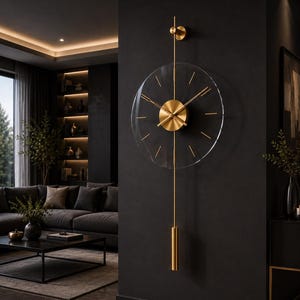 May include: A wall clock featuring a circular transparent acrylic face with gold-colored metal hour markers and central hands. A vertical gold metal rod extends above and below the clock face, ending in a cylindrical gold weight at the bottom.