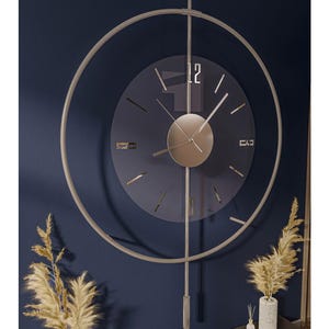 Könnte beinhalten: Eine moderne Wanduhr mit minimalistischem Design. Die Uhr hat ein kreisförmiges Zifferblatt mit silbernem Rahmen und Zeigern. Das Zifferblatt ist dunkelblau mit silbernen Stundenmarkierungen. Die Uhr ist an einer dunkelblauen Wand befestigt.