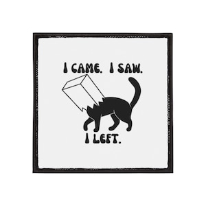 Pode incluir: Patch quadrado com borda preta e fundo branco. O patch apresenta um gato preto usando um saco de papel na cabeça, com o texto "I CAME. I SAW. I LEFT." em preto.