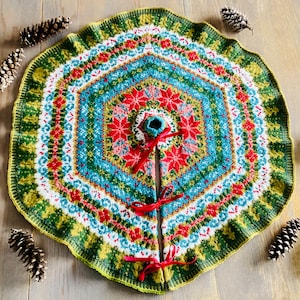 May include: A green, red, blue, and white knitted Christmas tree skirt with a snowflake pattern. The skirt is decorated with red ribbon bows.