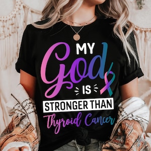 May include: Black t-shirt with the text "MY God IS STRONGER THAN Thyroid Cancer" in a gradient of purple, pink, and blue. The shirt features a ribbon graphic in teal and pink.