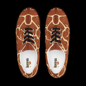May include: A pair of low-top sneakers featuring a brown and cream giraffe-inspired pattern across the exterior. The shoes have black laces, silver-toned eyelets, and white interior linings with the brand name Insan printed on the insoles.