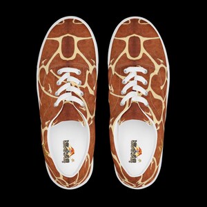 May include: A pair of low-top sneakers featuring a brown and cream giraffe print pattern across the exterior. The shoes have white laces, white rubber soles, and white interior linings with the text "insaan" printed on the heel of the insole.