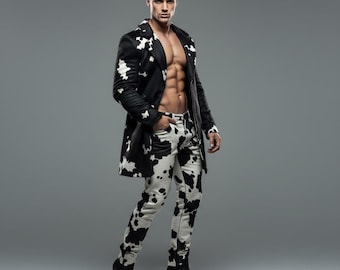 May include: A black and white cow print coat and matching pants. The coat is open, revealing a muscular torso. The pants and coat have a black and white pattern. The person is wearing black boots.