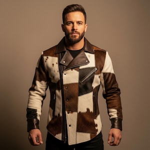 Peut inclure: Veste en cuir patchwork avec un motif de peau de vache marron, noir et blanc. La veste présente une fermeture éclair asymétrique classique, un col cranté et des poches zippées. Les manches ont des poignets en cuir marron.