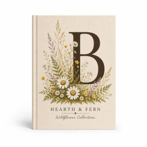 May include: A hardcover book with a cream-colored fabric cover featuring a large dark brown letter B surrounded by a botanical illustration of white daisies, yellow wildflowers, and green ferns. The text reads HEARTH & FERN Wildflower Collection.