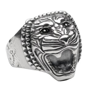May include: A silver ring with a detailed, snarling tiger head design. The ring has a textured band.