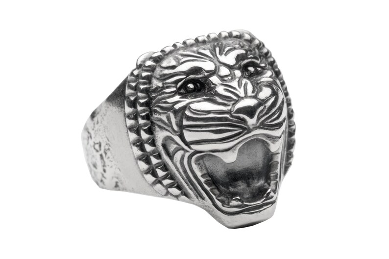 May include: A silver ring with a detailed, snarling tiger head design. The ring has a textured band.