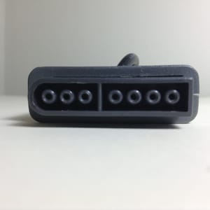 May include: A gray connector with eight round holes, likely for a video game console.