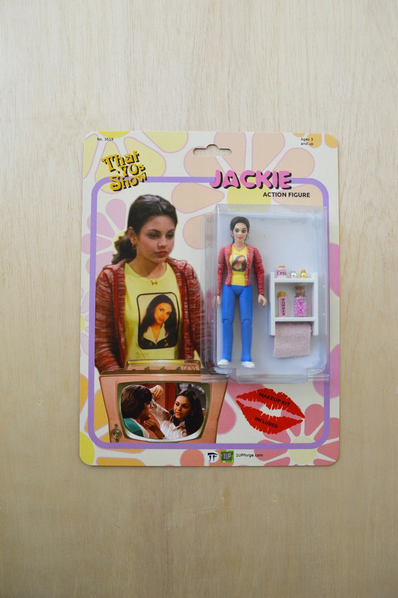 May include: A retro-style action figure of Jackie from the TV show "That 70s Show". The figure is wearing a red shirt, blue jeans, and a yellow shirt with a picture of Jackie on it. The figure is holding a small bottle of perfume and a towel. The figure is packaged in a cardboard box with a picture of Jackie on the front. The box also includes the text "Jackie Action Figure" and "Makeup Kit Included".
