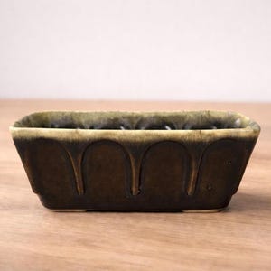 May include: A set of three ceramic mugs with a speckled, matte finish. The mugs are in shades of cream, light grey, and dark grey. Each mug has a simple, minimalist design, ideal for coffee or tea.