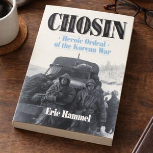 May include: A hardcover book titled "CHOSIN" with the subtitle "Heroic Ordeal of the Korean War" by Eric Hammel. The cover features a black and white image of soldiers and a military vehicle.