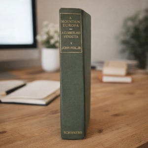 May include: A dark green hardcover book standing upright with gold lettering on the spine. The text reads A MOUNTAIN EUROPA, A CUMBERLAND VENDETTA, JOHN FOX JR., and SCRIBNERS. The book has a textured fabric cover and a rectangular shape.