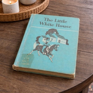 May include: A white ceramic mug with a black handle and the text "But first, coffee" in a black, handwritten-style font. The mug is on a white surface.