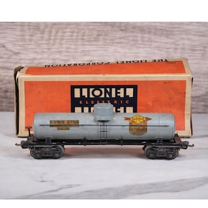 Könnte beinhalten: Vintage Modellzug SUNX 2755 der Lionel Electric Corporation. Der graue Tankwagen hat schwarze Räder und eine Leiter. Die Box ist orange mit dem Lionel-Logo. Das Sunoco-Logo ist sichtbar.