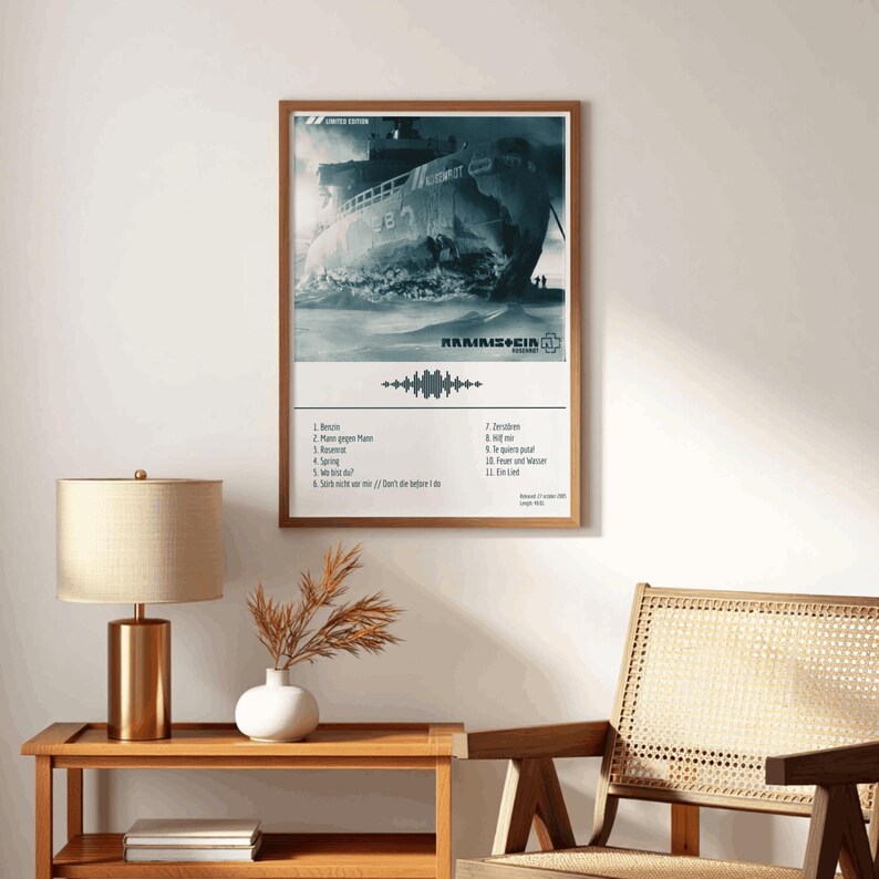 May include: A framed poster featuring a grayscale image of a ship in rough waters. The poster includes the band name "Rammstein" and a list of song titles. The frame is a warm brown color.