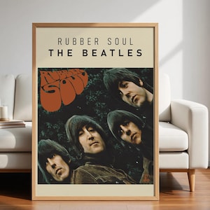 May include: A framed poster featuring the album art for The Beatles' "Rubber Soul." The poster has a beige background with the album title and band name in black text. The album art shows the band members' faces. The word "Soul" is in orange.