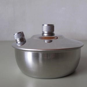 Może przedstawiać: Zestaw trzech ceramicznych kubków z nakrapianym, matowym wykończeniem. Kubki są w odcieniach kremu, jasnoszarym i ciemnoszarym. Każdy kubek ma prosty, minimalistyczny design.