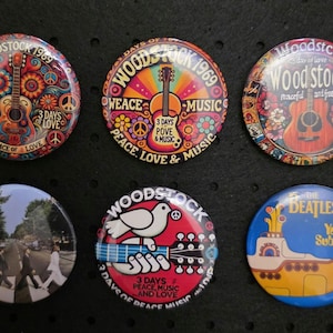 Könnte beinhalten: Sechs runde Ansteckbuttons mit farbenfrohen Designs, die sich auf das Woodstock-Musikfestival und die Beatles beziehen. Die Buttons zeigen Gitarren, Friedenszeichen und das Yellow Submarine. Die Buttons sind farbenfroh.