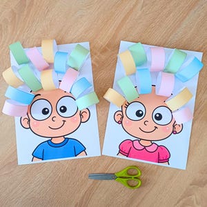 May include: Two paper craft sheets featuring cartoon faces with large eyes and smiles, decorated with colorful pastel paper loops attached to the top to resemble hair. A pair of green scissors is positioned below the two illustrated paper sheets.