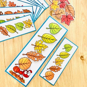 Puede incluir: Una colección de marcapáginas rectangulares con ilustraciones coloridas de hojas de otoño en tonos verdes, amarillos, naranjas y marrones, con un marcapáginas que muestra una hormiga dibujada cargando una hoja grande, además de pegatinas.
