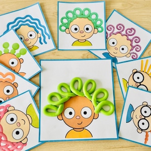 Peut inclure: Une collection de cartes d'activités carrées représentant des visages de dessins animés avec des têtes vides. Chaque carte montre un personnage avec différentes coiffures créées à l'aide de pâte à modeler colorée, incluant des vagues bleues, des boucles vertes, des spirales violettes et des pointes jaunes.