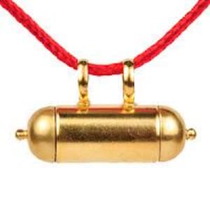 May include: A gold-colored cylindrical pendant with rounded ends, suspended from a bright red cord. The pendant has two small loops at the top and a small knob on each end. The background is plain white.