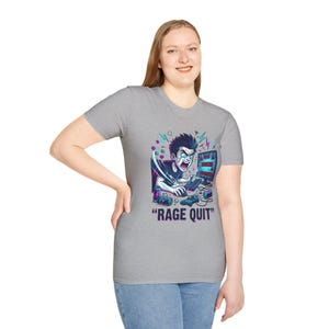 Könnte beinhalten: Graues T-Shirt mit einem farbenfrohen Grafikdesign einer Person, die intensiv Videospiele spielt, mit dem Text "RAGE QUIT" darunter. Die Grafik zeigt einen Computer, einen Controller und Blitze.