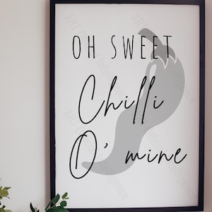 Op de afbeelding: Zwart omkaderde wandkunst met de tekst "Oh Sweet Chilli O' mine" in een handgeschreven lettertype. Achter de tekst staat een grijze chilipepervorm. Links staat een groene plant in een grijze pot.