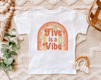 May include: White t-shirt with a colorful rainbow graphic and the text "Five is a Vibe". The design includes flowers, stars, and a smiley face. A fun and cheerful design for a child's birthday.