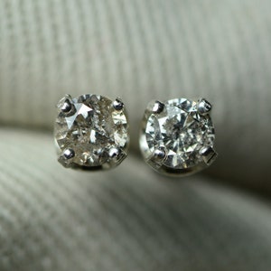 May include: A pair of silver stud earrings with small round clear diamonds.