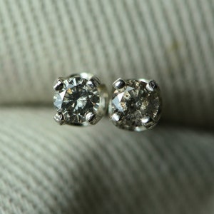 May include: A pair of silver stud earrings with small, clear, round diamonds.