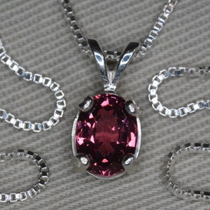 Könnte beinhalten: Eine silberne Kettenkette mit einem rosa ovalen Edelstein-Anhänger.
