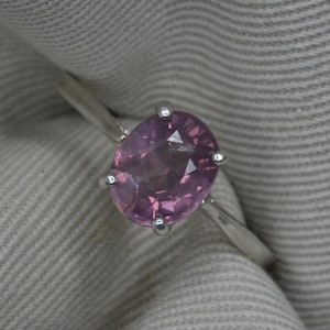 May include: A silver ring with a pink oval gemstone set in a four-prong setting.