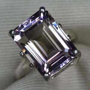 Puede incluir: Un anillo de plata con una gran piedra de amatista rectangular de color púrpura claro.