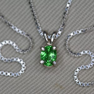 May include: A silver chain necklace with a green oval gemstone pendant.