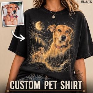 May include: A black t-shirt featuring a graphic print of a brown dog wearing a pink collar. The design includes a smaller dog standing in a forest landscape under a full moon, with a larger portrait of the same dog overlaid above the trees.