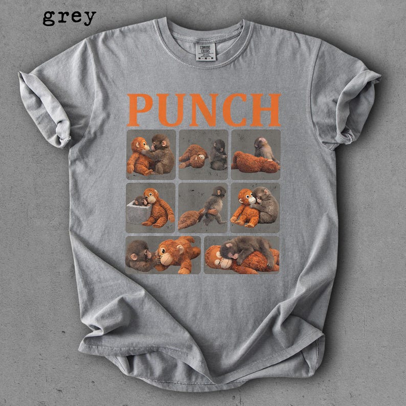Peut inclure: T-shirt gris avec le mot "PUNCH" en lettres orange. Le t-shirt pr&eacute;sente une grille de neuf carr&eacute;s, chacun contenant une illustration diff&eacute;rente de deux singes qui s'embrassent. Le mot "grey" est dans le coin sup&eacute;rieur gauche.