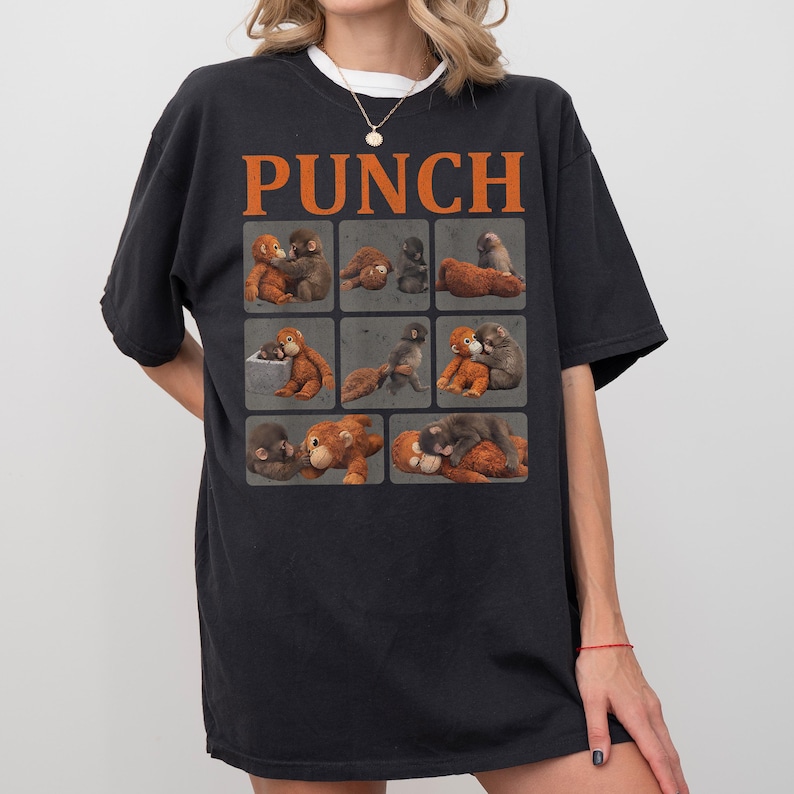 Peut inclure: T-shirt noir avec le mot "PUNCH" en lettres orange. Le t-shirt pr&eacute;sente une grille de neuf images de singes dans diverses poses. Les singes sont dans des tons de marron et de gris.